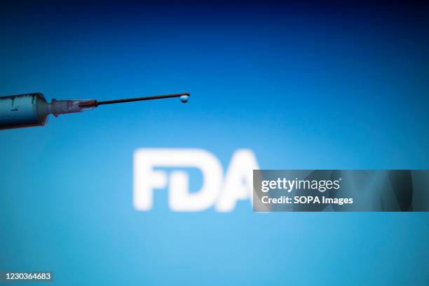 In this photo illustration a medical syringe is seen with FDA logo FDA approved Pfizer / BioNTech and Moderna COVID-19 coronavirus vaccine for...