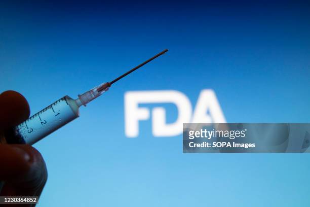 In this photo illustration a medical syringe is seen with FDA logo FDA approved Pfizer / BioNTech and Moderna COVID-19 coronavirus vaccine for...