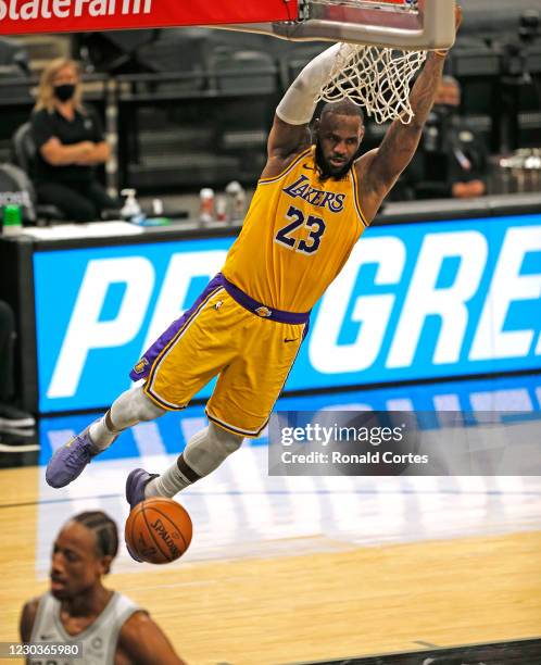 LeBron James of the Los Angeles Lakers hangs onto the rim after dunking past DeMar DeRozan of the San Antonio Spurs during second half action at AT&T...