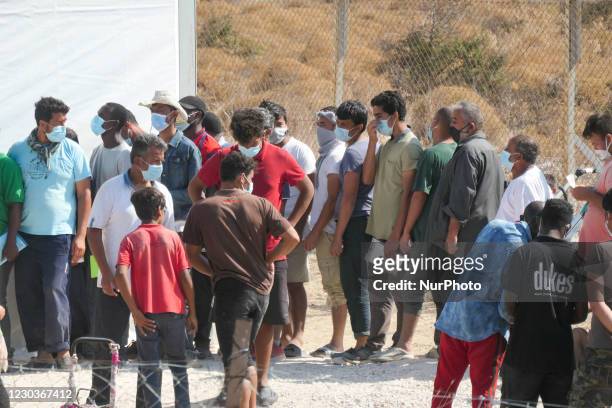 New Temporary Refugee Camp in Kara Tepe - Mavrovouni with large white tents having the UNHCR or UNICEF logo and asylum seekers waiting in line for...