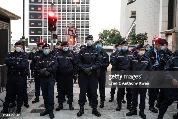 Police officers stand guard as a Correctional Service Department vehicle carrying Hong Kong media tycoon, Jimmy Lai, founder and owner of Apple Daily...