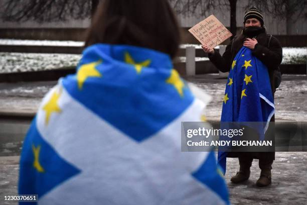 An anti-Brexit pro-Scottish independence activist wrapped in an EU flag holds a placard during a small protest against Britain's exit from the...