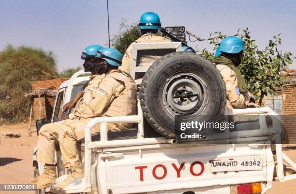 Members of the United Nations and African Union peacekeeping mission ride in the back of a truck in Kalma camp for internally displaced people in...