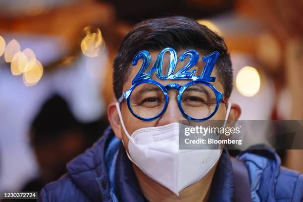 Pedestrian wears a protective mask and novelty "2021" glasses near the Times Square area of New York, U.S., on Thursday, Dec. 31, 2020. The annual...
