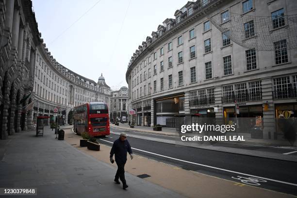 Pedestrian walks along a near-deserted Regent Street in central London on January 1, 2021. - Britain today began a new year and life outside Europe,...