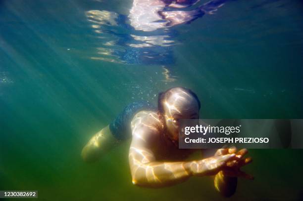 Man dives into the cold water for a swim during the annual polar bear plunge at the M Street beach in South Boston, Massachusetts on January 1, 2021....