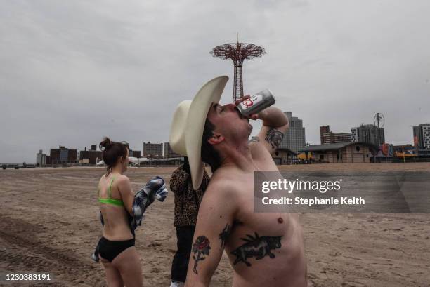 Man drinks a beer during a New Year's Day plunge into the Atlantic Ocean off of Coney Island on January 1, 2021 in the Brooklyn borough of New York...