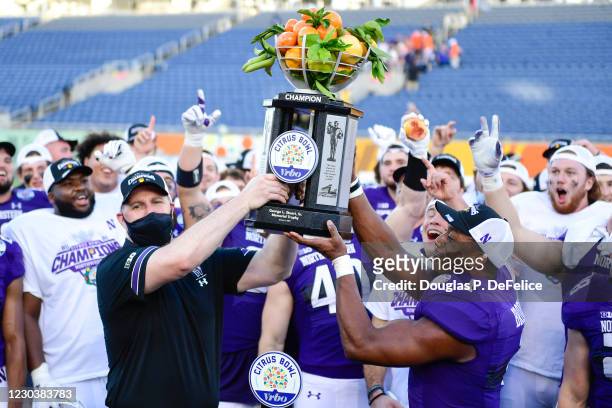 Head coach Pat Fitzgerald and Jesse Brown of the Northwestern Wildcats raise the trophy after defeating the Auburn Tigers to win the Vrbo Citrus Bowl...