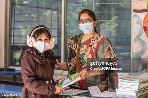 Teacher hands a new textbook over to one of her students at the Viqarunnisa Noon School in Dhaka. The nationwide textbook distribution among the...