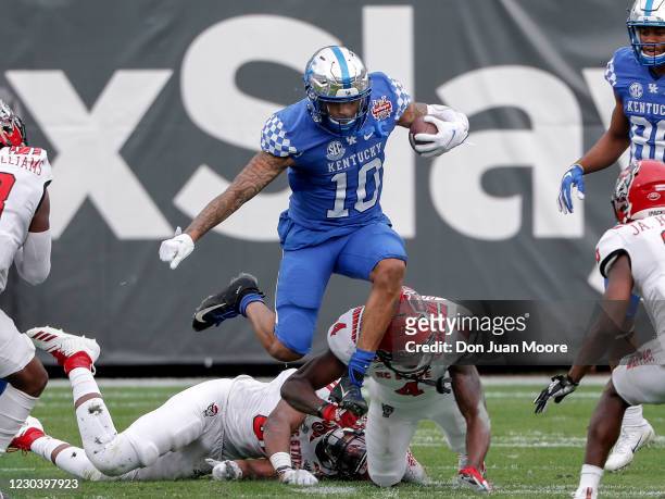 Runningback Asim Rose of the University of Kentucky Wildcats leaps over Defensive Back Cecil Powell of the North Carolina State Wolfpack on a running...