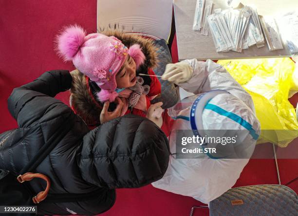 This photo taken on January 2, 2021 shows a health worker taking a swab sample from a child, to be tested for the Covid-19 coronavirus at a temporary...