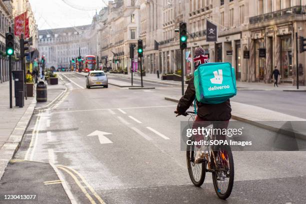 Deliveroo courier rides along the Regent Street delivering Takeaway food in central London during covid 19 tier 4 restrictions.