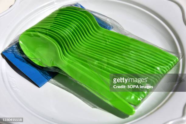 In this photo illustration small green plastic spoons placed on a white plastic plate. Since January 1 many single-use plastic items have been banned...