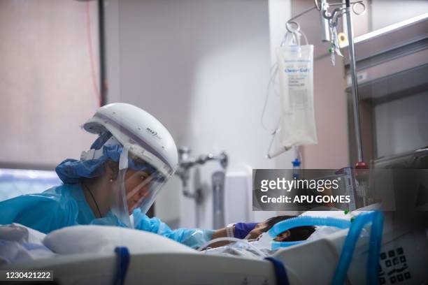 Registered nurse Yeni Sandoval wears personal protective equipment while she cares for a Covid-19 patient in the Intensive Care Unit at Providence...