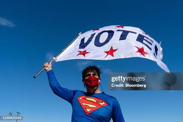 Supporter dressed as Superman holds a "VOTE" flag at a campaign event for Raphael Warnock, U.S. Democratic Senate candidate, in Riverdale, Georgia,...