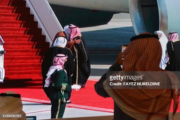 Journalists watch, Saudi Crown Prince Mohammed bin Salman welcomes the Emir of Qatar Tamim bin Hamad Al-Thani, on a screen in the media centre ahead...