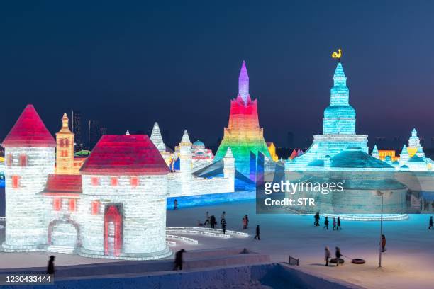 This photo taken on January 4, 2021 shows people looking at ice sculptures at the Harbin Ice and Snow Festival in Harbin, in northeastern China's...