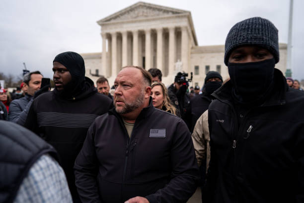 Flanked by personal security, Alex Jones leaves after speaking at a Stop the Steal rally in front of the Supreme Court on Tuesday, Jan. 5, 2021 in...