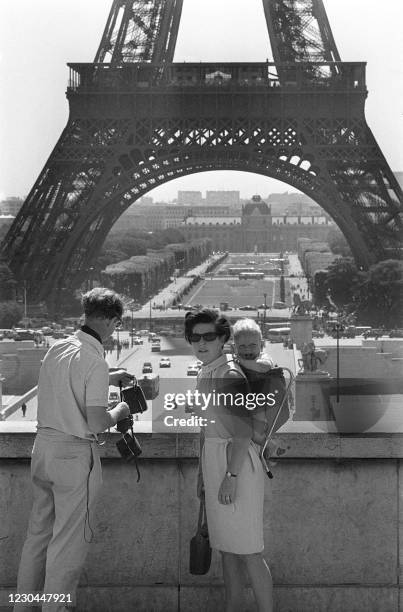 American tourists visit the Eiffel Tower July 11, 1967 in Paris. Thanks to a judicious installation, it is on the back of his mum that the baby will...