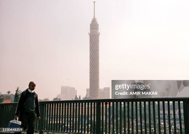 Man walks along the side of the October 6 bridge connecting Egypt's twin districts of Cairo and Giza, over the capital's Nile island of Zamalek on...