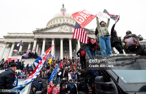 Trump supporters stand on the U.S. Capitol Police armored vehicle as others take over the steps of the Capitol on Wednesday, Jan. 6 as the Congress...
