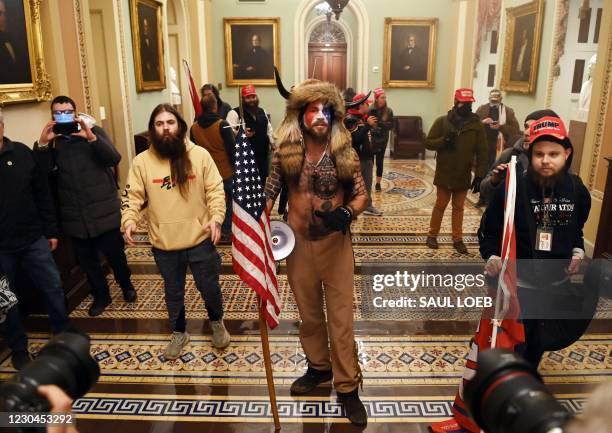 Supporters of US President Donald Trump, including Jake Angeli , a QAnon supporter known for his painted face and horned hat, enter the US Capitol on...