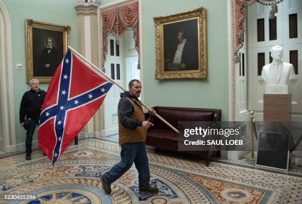 Supporter of US President Donald Trump carries a Confederate flag as he protestS in the US Capitol Rotunda on January 6 in Washington, DC. -...