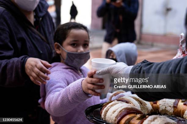 Migrant girl receives a hot chocolate as advocates serve traditional Rosca de Reyes and give presents to migrant children during the Epiphany's day...