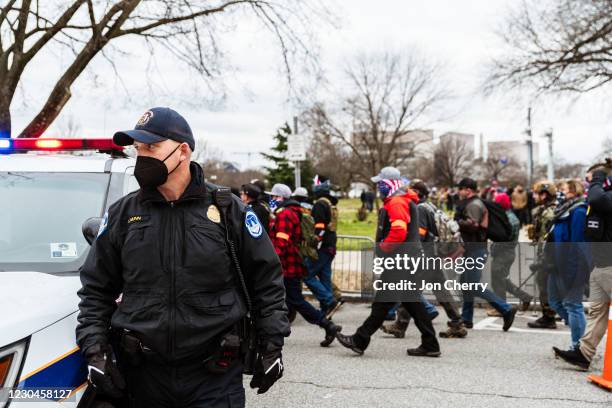 Capitol Police officer watches as pro-Trump protesters march in front of the U.S. Capitol Building on January 6, 2021 in Washington, DC. A pro-Trump...