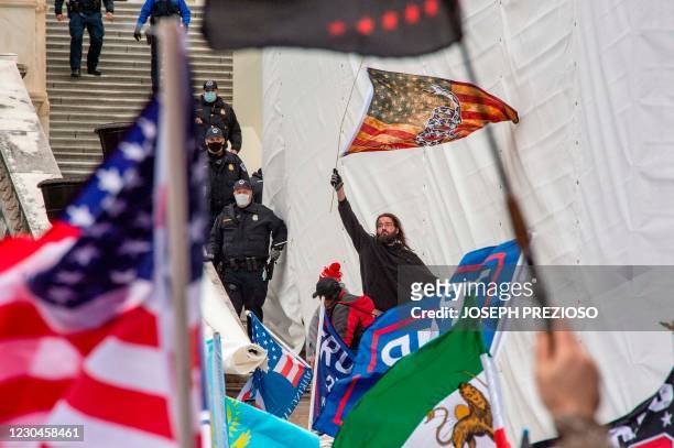 Man waves a flag from the stairs of the US Capitol Building after breaking a police line as protesters and supporters of US President Donald Trump...