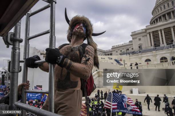 Jacob Chansley, a protester, climbs scaffolding as demonstrators swarm the U.S. Capitol building in Washington, D.C., U.S., on Wednesday, Jan. 6,...