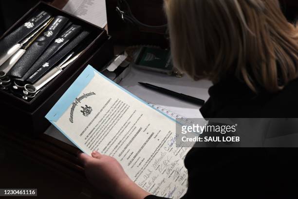Person holds the certificate of votes from the commonwealth of Pennsylvania during a joint session of Congress after the session resumed following...