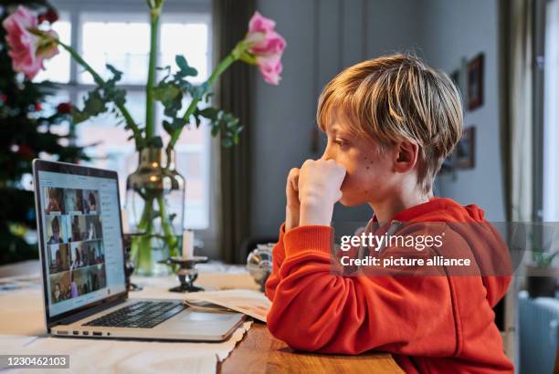 January 2021, Berlin: An elementary school student sits in front of a screen at home, using a laptop to participate in online classes with a teacher....