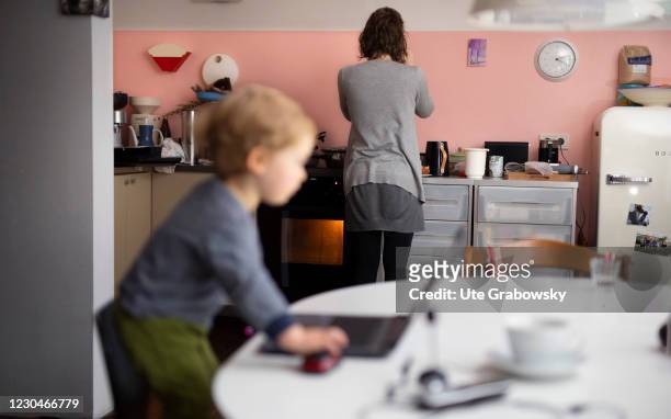 Bonn, Germany In this photo illustration a mother is doing homework while the child has climbed up a chair and is olaying with her laptop on January...