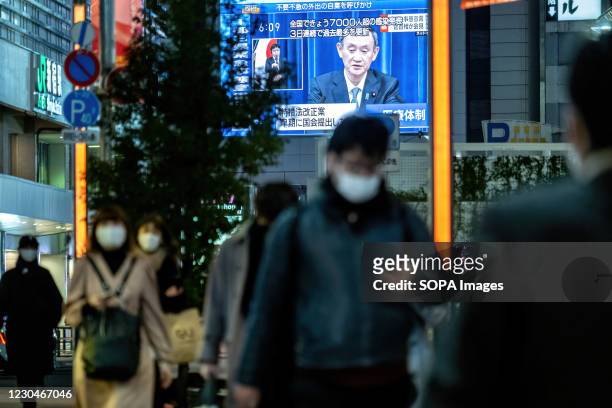 People seen wearing facemasks as a preventive measure against Covid-19 with a live broadcast of Japan's Prime Minister Yoshihide Suga declaring a...