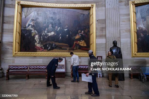 Members of the office of the Architect of the US Capitol check for damage in the Rotunda in Washington, DC, on January 7 one day after supporters of...