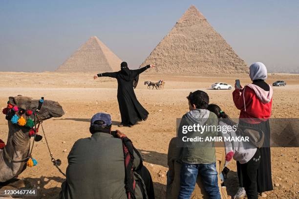 Fully-veiled woman strikes a pose while being photographed by other tourists at the Giza Pyramids Necropolis on the outskirts of Egypt's capital...