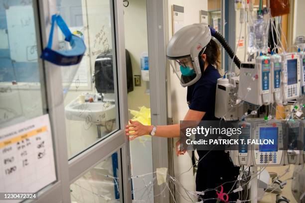 Nurse wearing personal protective equipment including a personal air purifying respirator closes a door to a patients room in a Covid-19 intensive...