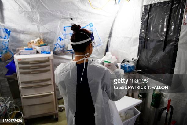 Nurse removes personal protective equipment after attending to patients in a suspected Covid-19 patient triage area set up in a field hospital tent...