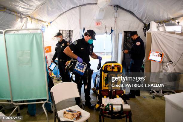 An ambulance emergency medical technician packs up equipment while wearing personal protective equipment after transferring a patient to a suspected...