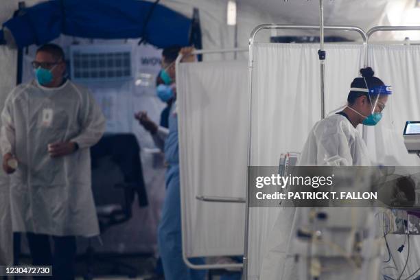 Nurse wearing personal protective equipment attends to a patient in a suspected Covid-19 patient triage area set up in a field hospital tent outside...