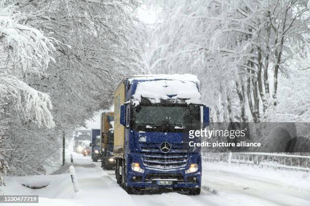 January 2021, North Rhine-Westphalia, Roetgen: Cars and trucks are stuck in traffic on the B258 near Roetgen. Snow and icy roads have caused...
