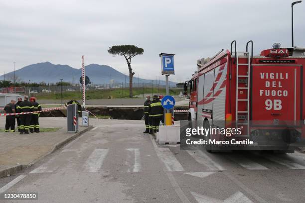 Firefighters in front of the huge chasm that has opened up, following an explosion, in the parking lot of the Ospedale del Mare in Naples, in the...
