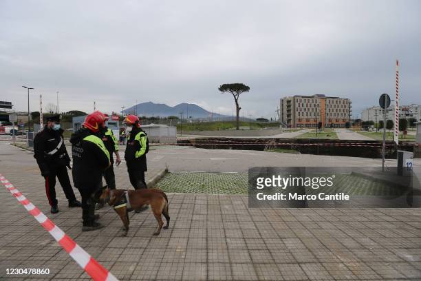 Firefighters, with a rescue dog, in front of the huge chasm that has opened up, following an explosion, in the parking lot of the Ospedale del Mare...