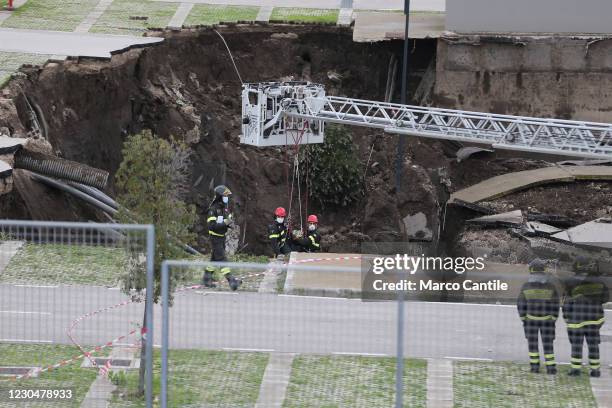 Two firefighters descend into the huge chasm that opened, following an explosion, in the parking lot of the Ospedale del Mare in Naples, in the...