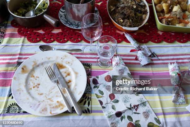 An empty plate, wine glass and a table of food leftovers, the remnants of Christmas excess on Christmas Day, on 25th December 2020 in London,...