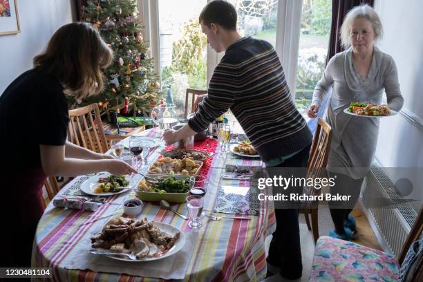 Members of a British family help themselves to a turkey and vegetables Christmas Day lunch, on 25th December 2020 in London, England. Christmas lunch...