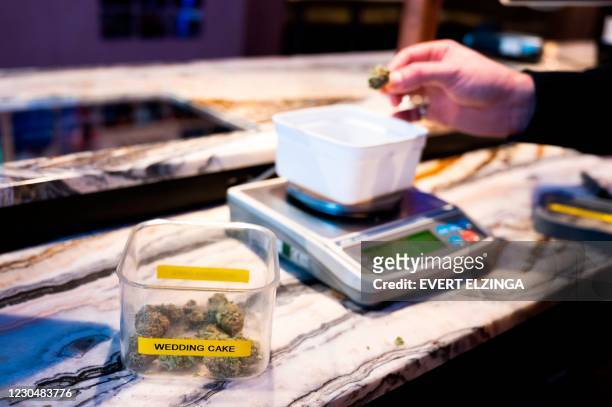 Teller weighs marijuana for a customer in a coffee shop in the city centre of Amsterdam on January 8, 2021. - Amsterdam's ecologist mayor on January...