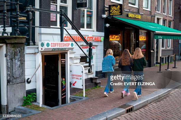 Pedestrian walk past coffee shops in the city centre of Amsterdam on January 8, 2021. - Amsterdam's ecologist mayor on January 8 proposed banning...