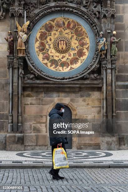 Man wearing a face mask as a preventive measure against the spread of coronavirus walks under an astronomical clock at the Old town square in Prague.